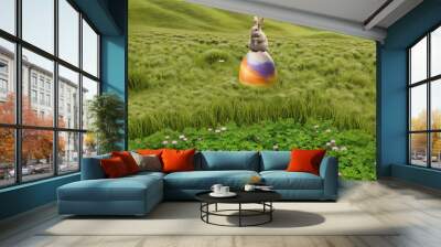 A bunny sitting on an enormous colorful Easter egg in a sloping grassland meadow Wall mural