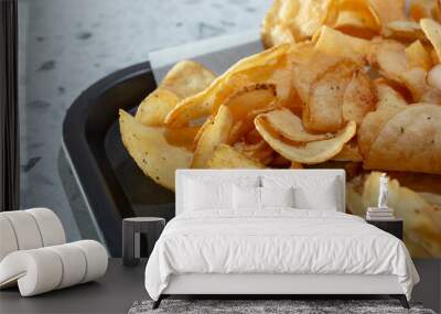 A closeup view of a pile of homemade potato chips on a tray. Wall mural