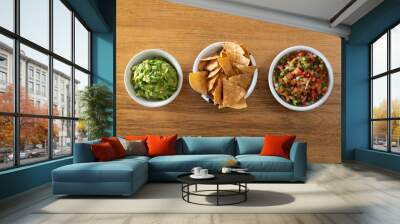 A top down view of guacamole, tortilla chips and pico de gallo salsa. Wall mural