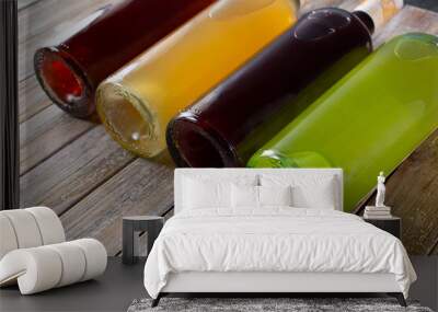 A view of several brightly colored bottles of juice or alcohol laying down on a wooden table surface. Wall mural