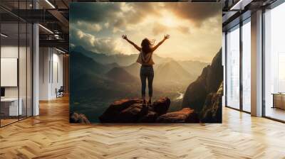 A young woman reaches the top of a mountain and celebrates with arms wide open. Concept: Success in life Wall mural