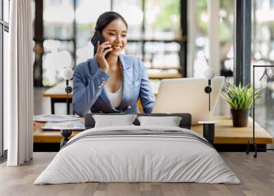 Asian Businesswoman Using laptop computer and working at office with calculator document on desk, doing planning analyzing the financial report, business plan investment, finance analysis concept. Wall mural