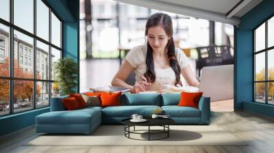 Asian young business woman working on laptop computer reading financial document report in office. Accountant entrepreneur manager businesswoman doing paperwork. Copy space Wall mural