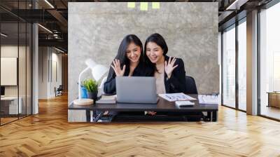 Asian Young Businesswoman attending video conference on laptop computer online co worker leaning at office monitor with professional working Wall mural