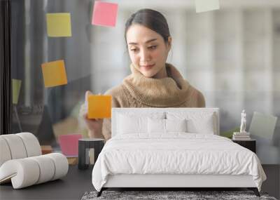 Business Asian woman meeting at office and use post it notes in glass wall to share idea. Brainstorming business office concept. Sticky note on glass wall. Wall mural