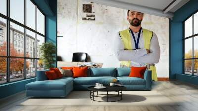 Construction worker, portrait and man with arms crossed in office or building site for architecture project. Architect, engineer or serious male contractor, leader or engineering manager at workplace Wall mural