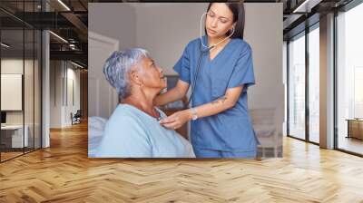 Doctor, stethoscope and senior woman with caregiver checking health, heart rate and beat at home. Young female healthcare GP or nurse helping elderly patient check heartbeat for medical care indoors Wall mural