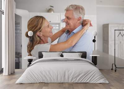 Happy senior couple, love and hug for care in joyful relationship together in the kitchen at home. Elderly man and woman smile, dancing and sharing a bonding moment of romance at the house Wall mural