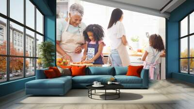 Black family cooking, children learning and grandmother teaching girl for healthy lunch and growth development in kitchen together. Senior woman and mom with kids make salad or vegetable food in home Wall mural