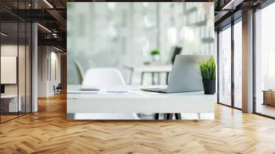 laptop computer, notebook, and eyeglasses sitting on a desk in a large open plan office space after  Wall mural