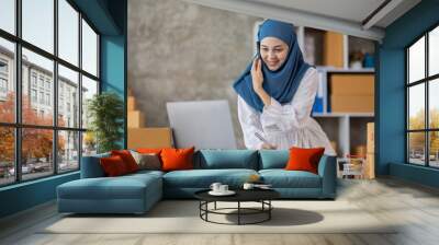 Muslim young Asian woman working at home doing sme ecommerce online small business entrepreneur checking postal parcels to delivery to online customers, startup Muslim Sme business concept. Wall mural