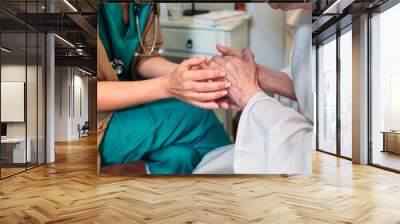 Female doctor giving encouragement to elderly patient by holding her hands Wall mural