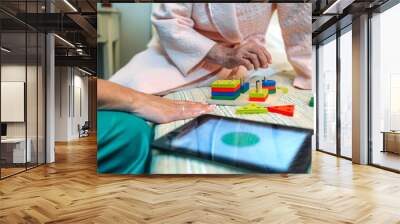 Female doctor showing geometric shape game to elderly female patient with dementia Wall mural