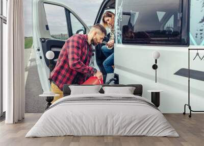 Man refueling his camper van with a jerrycan Wall mural