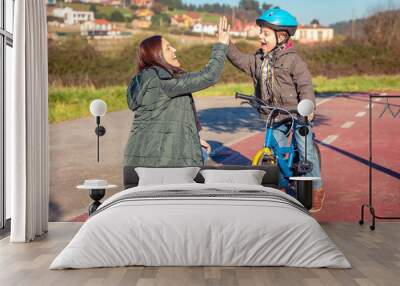 Mother and son giving five by success riding bicycle Wall mural