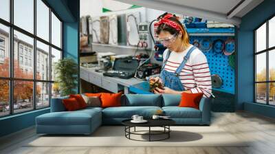 Portrait of mechanic woman with safety glasses checking caliper brake system in front of workbench on factory Wall mural