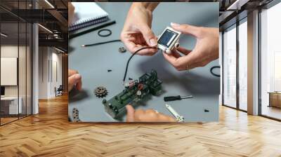 Unrecognizable female teacher explaining to girl student how connect a solar panel on electrical circuit in a robotics class. Elementary technological education concept. Wall mural