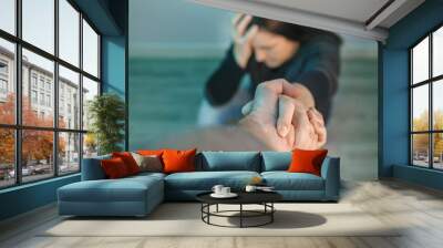 Unrecognizable woman with mental health problems receiving help from man holding her hand. Helping hand concept Wall mural