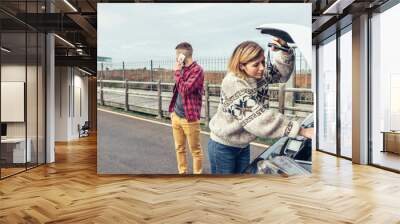 Woman repairing broken down campervan while her husband calls on the phone Wall mural