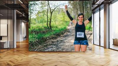 Young woman winning a trail race in the forest Wall mural