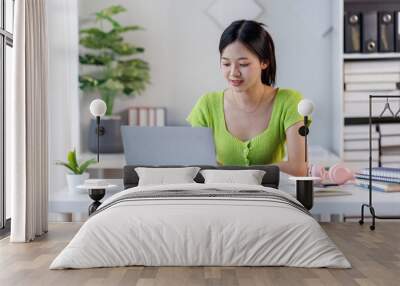 Portrait of a modern business asian woman, woman in a green shirt working on a laptop in the home office
 Wall mural