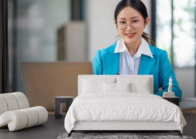 Portrait of asian young female entrepreneur sitting at her desk in the office Wall mural