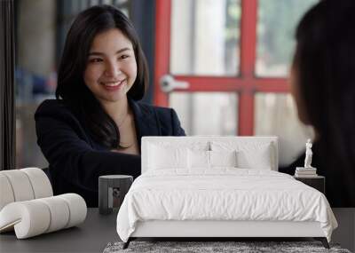 Pretty Young Asian business woman shaking hands with business in her office during a meeting Wall mural