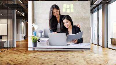 Shot of two Asian businesswoman working together on a new startup project Idea presentation, analyze planning and financial statistics and investment market at the office. Wall mural