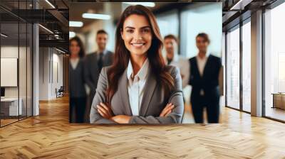 Smiling attractive confident professional woman posing at her business office with her coworkers and employees in the background Wall mural