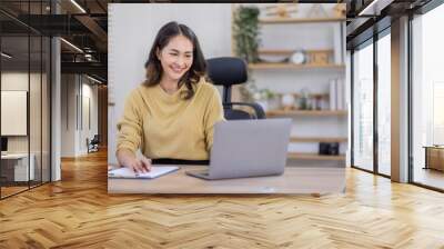 Smiling indian woman using laptop at home, Happy Young asian  businesswoman send email and working at home. Asian freelancer typing on computer with paperworks and documents on table. Wall mural