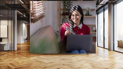 Young confident pretty Asian woman working with laptop and credit card on sofa at home, shopping and online payment by using laptop with sun light effect. Wall mural