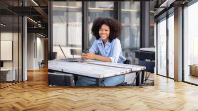 Young happy professional business woman worker employee sitting at desk working on laptop in corporate outside. Smiling female student using computer technology learning online, doing web research. Wall mural