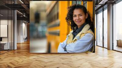 A confident female school bus driver standing next to her yellow bus. Wall mural