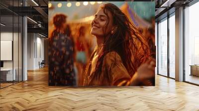 A young woman joyfully dances in the rain at a festival, illuminated by warm, glowing lights in the background. Wall mural