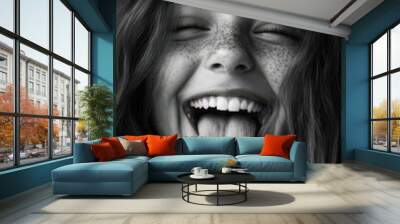 Black and white portrait of a cheerful girl with freckles playfully sticking out her tongue, radiating joy and spontaneity. Wall mural