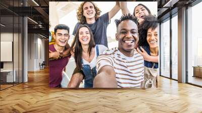 Group multiracial friends taking selfie picture with mobile smartphone outside - Happy young with hands up laughing at camera - Youth concept with guys and girls having fun walking on city street Wall mural