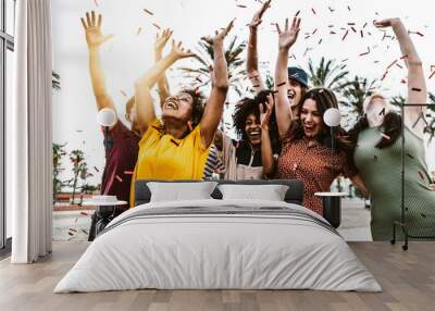 Group of friends enjoying party throwing confetti in the air - Multicultural young students having fun celebrating and laughing out loud outdoor - Youth, friendship and summertime concept Wall mural