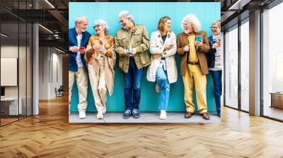 Group of senior people using technology devices together standing on a blue wall - Happy older friends having fun watching funny video on smartphone - Tech and modern elderly concept
 Wall mural