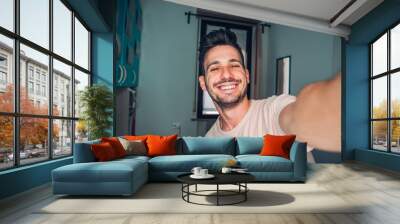 Handsome caucasian man taking a self portrait indoor at home Wall mural