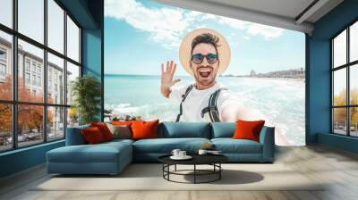 Handsome young man taking selfie at beach summer vacation - Smiling guy having fun walking outside - Summertime holidays and technology concept Wall mural