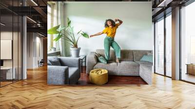 Happy afro american woman dancing on the sofa at home - Smiling girl enjoying day off lying on the couch - Healthy life style, good vibes people and new home concept Wall mural