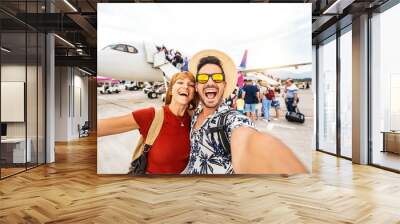 Happy couple of tourists boarding on a plane at the airport - Happy man and woman having happy summer vacation together - Transportation and holidays concept Wall mural