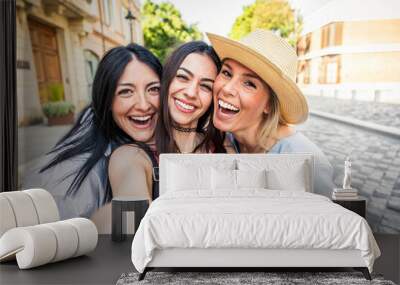 Happy female friends taking selfie with smart mobile phone device outside - Delightful young women having fun on summer vacation - Friendship concept with ladies enjoying day out Wall mural