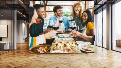 Happy friends drinking red wine sitting at restaurant table - Multiracial young people enjoying rooftop dinner party together - Food and beverage concept with guys and girls having lunch break outside Wall mural