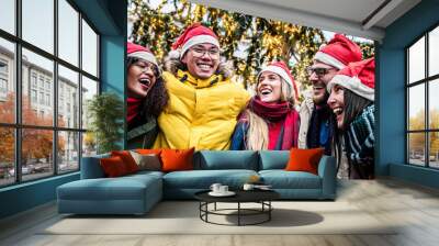 Happy friends wearing santa claus hat celebrating Christmas day in city street - Winter holidays life style concept Wall mural