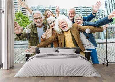 Happy group of senior people smiling at camera together outside - Delightful older friends enjoying day out walking on city street - Aged male and females pensioners hugging together outdoors Wall mural