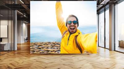 Happy man taking selfie on the top of the mountain - Millenial influencer on social media - Hiker on trekking excursion Wall mural