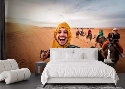 Happy tourist having fun enjoying group camel ride tour in the desert - Travel, life style, vacation activities and adventure concept Wall mural