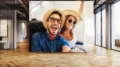 Happy tourist taking selfie inside airplane - Cheerful couple on summer vacation - Passengers boarding on plane - Holidays and transportation concept Wall mural