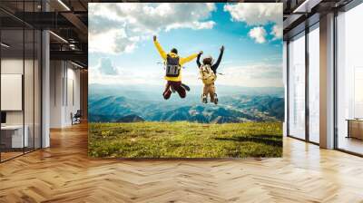 Hikers with backpack jumping with arms up on top of the mountain Wall mural